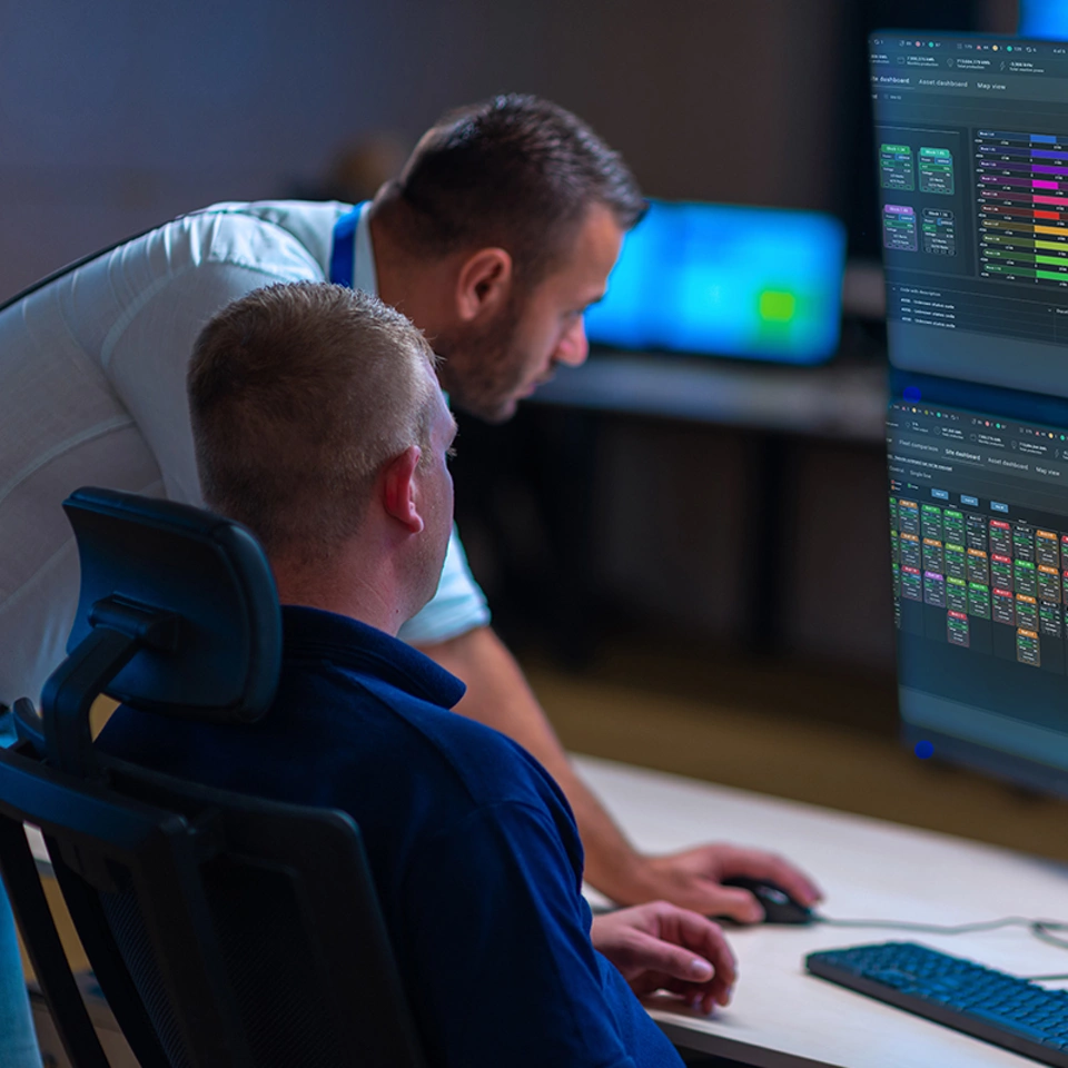 Group of Security data center operators (administrators) working in a group a monitoring room while looking at multiple SCADA monitors