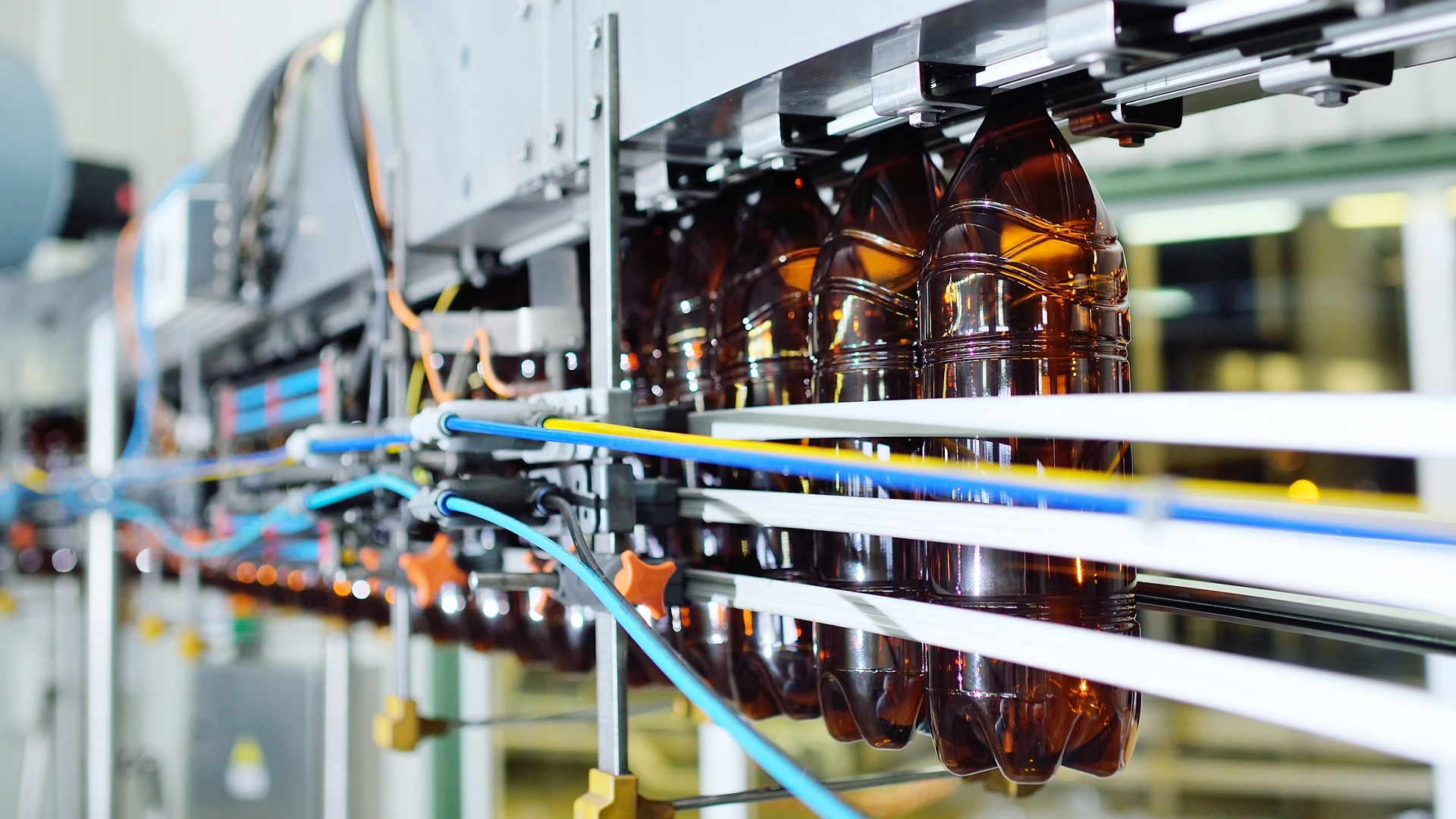 production of large-capacity plastic bottles for beverages, water and sunflower oil. Empty plastic PET bottles of yellow color on a conveyor belt.