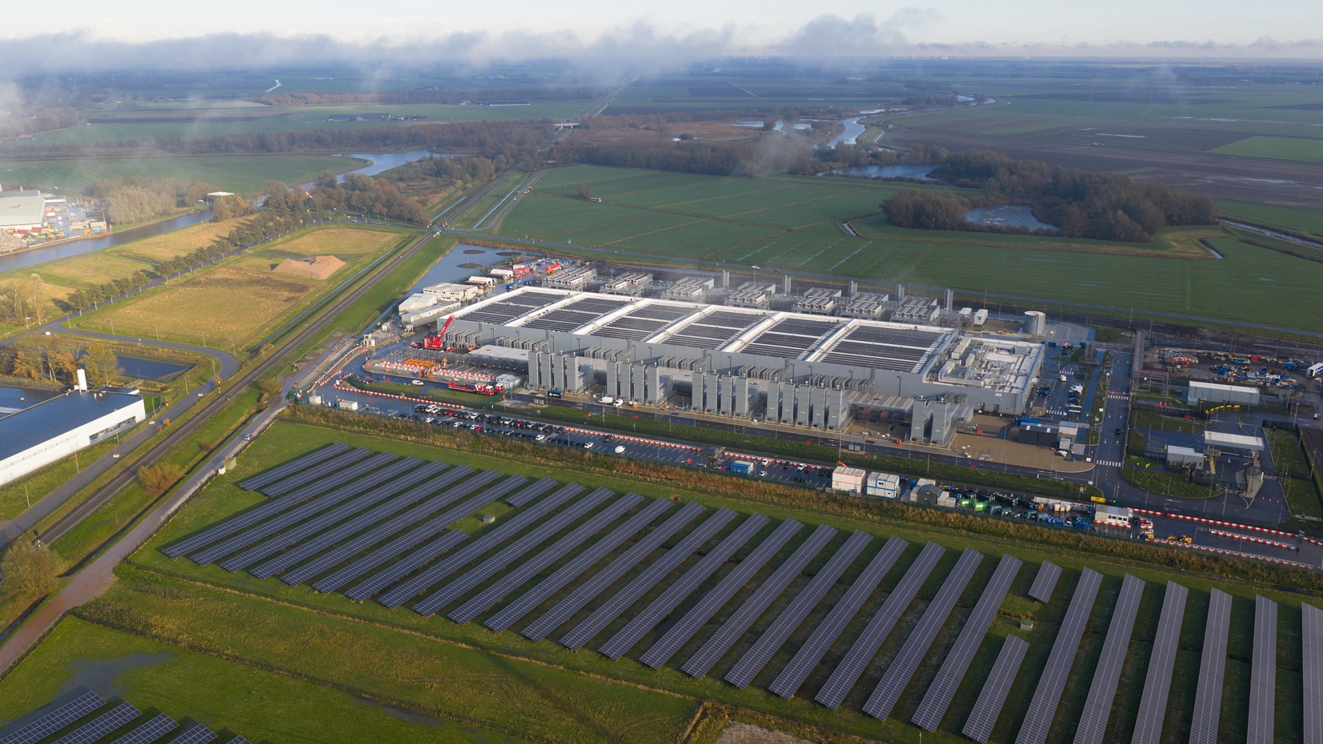Dynamic aerial drone close-up of a newly built hyperscale data center in Winschoten, Netherlands. This facility integrates cutting-edge AI infrastructure running on sustainable and renewable energy sources, showcasing the future of green technology.