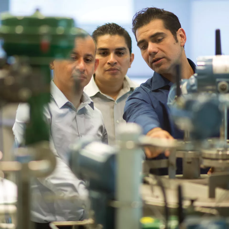 Three people in a training lab pointing to measurement products