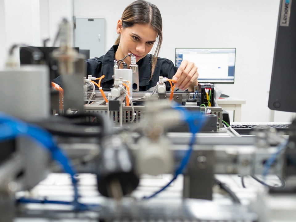 Computer science development engineer working on robotic arm connection and control at electronic futuristic technology center. Modern people training in industry 4.0 automated engineering workshop