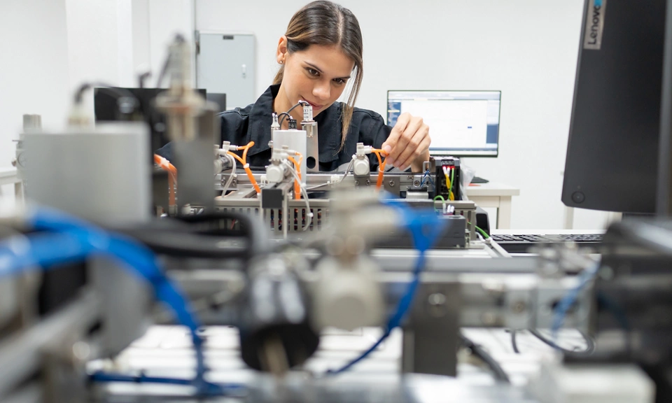Computer science development engineer working on robotic arm connection and control at electronic futuristic technology center. Modern people training in industry 4.0 automated engineering workshop