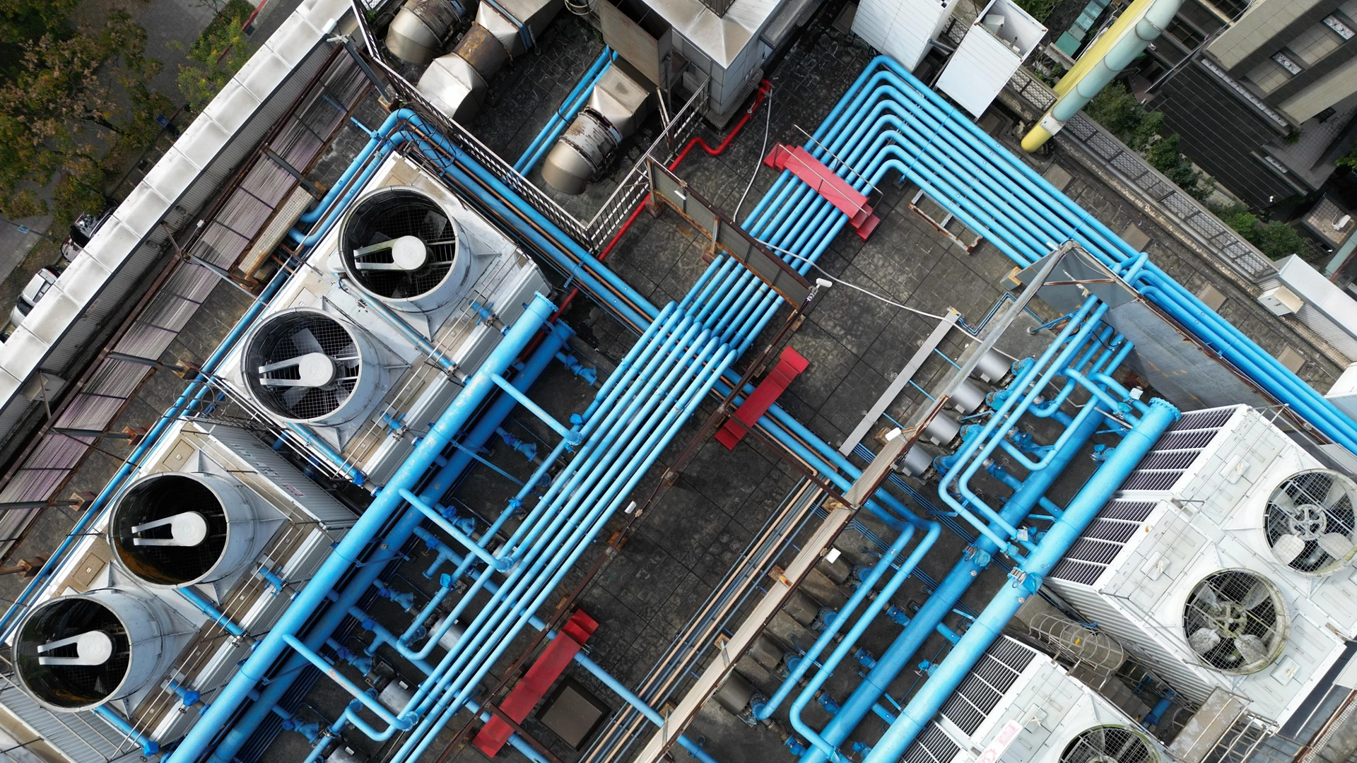 Top-down aerial view of data center rooftop cooling towers and complex blue piping infrastructure.
