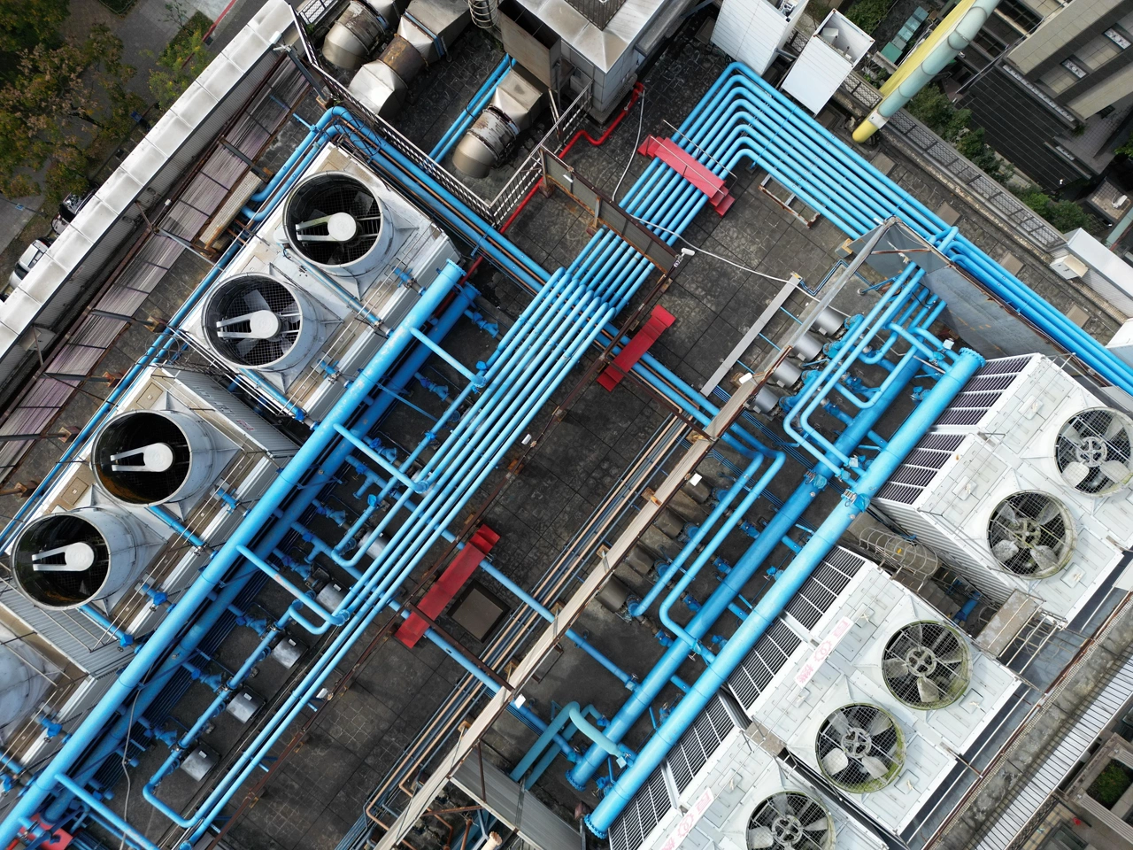Top-down aerial view of data center rooftop cooling towers and complex blue piping infrastructure.