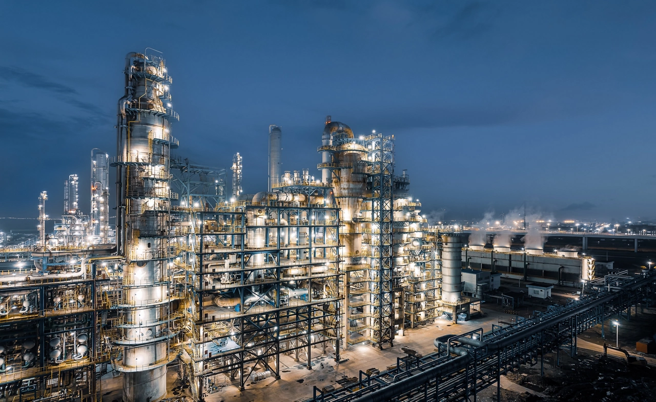 Industrial chemical plant equipment and pipelines at night view.