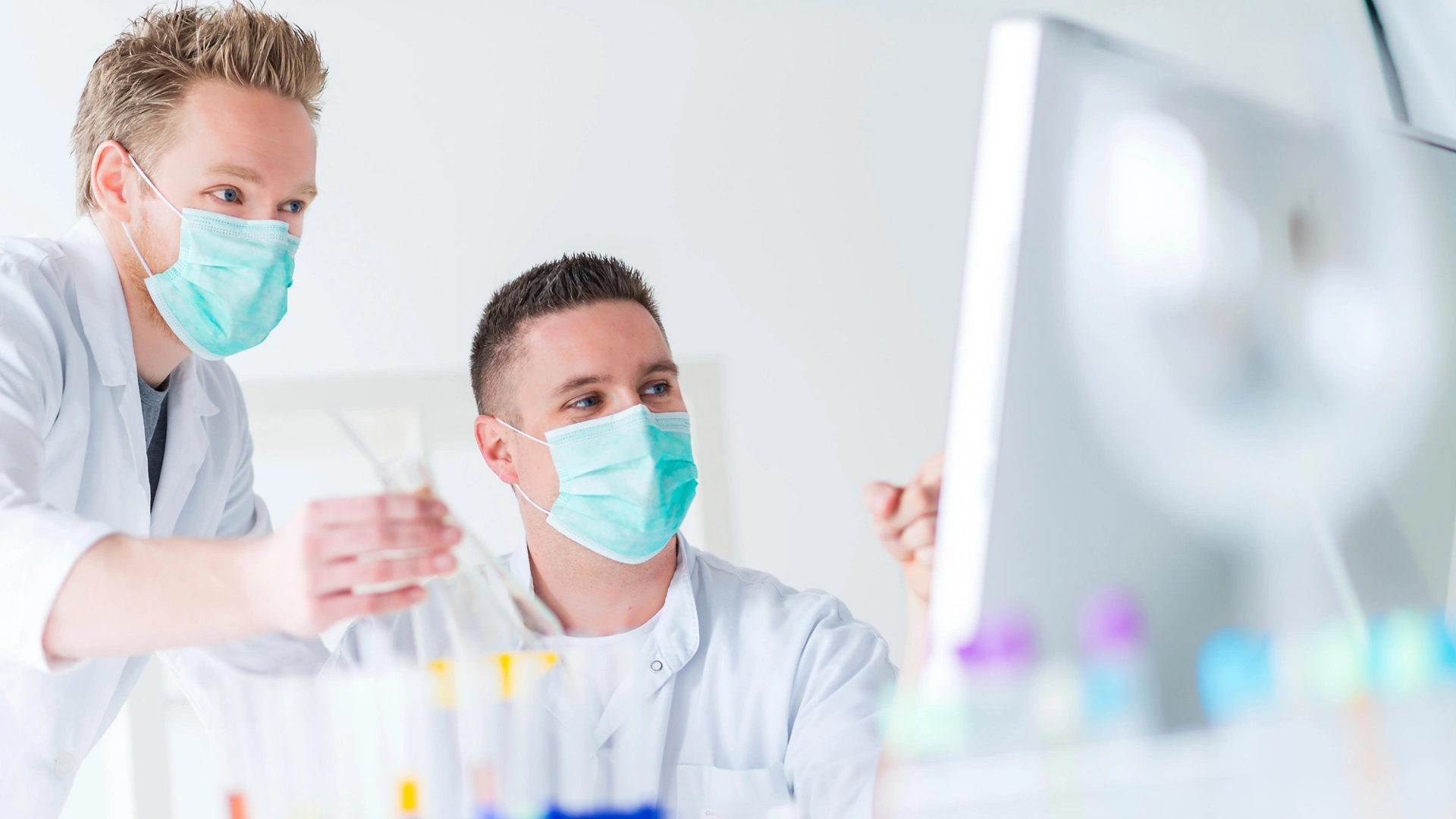 men wearing masks holding beakers in lab Biotech Firm Automates Document Management Save Time Money Improve Compliance