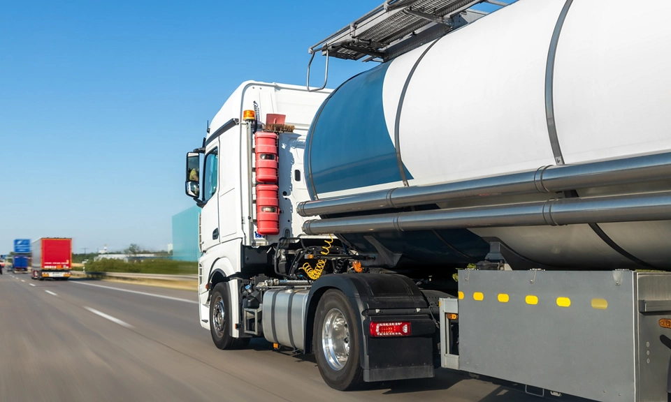 White big modern tanker shipment cargo commercial semi trailer truck moving fast on motorway road city urban suburb. Business distribution logistics service. Lorry driving highway sunny day.