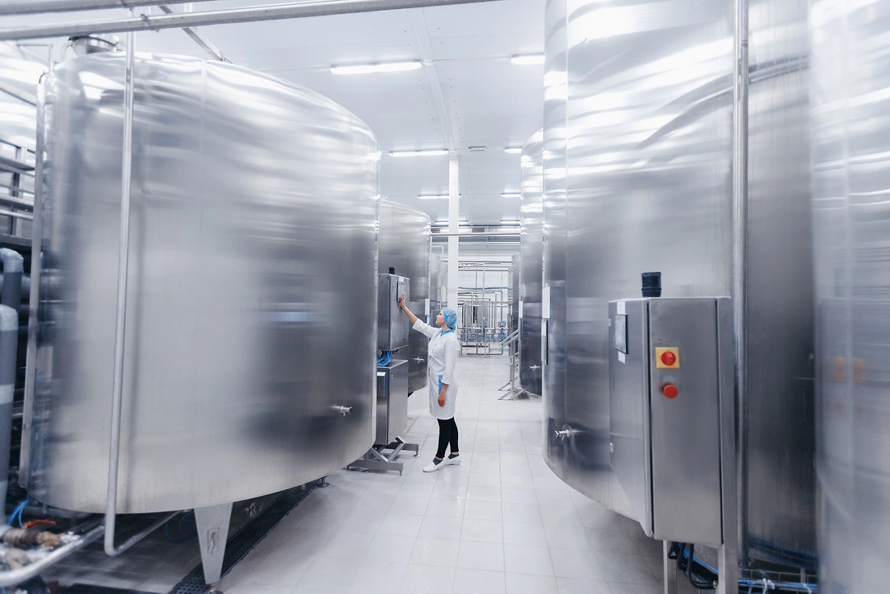 Operator female in uniform uses control panel manage process dairy plant food factory production line.