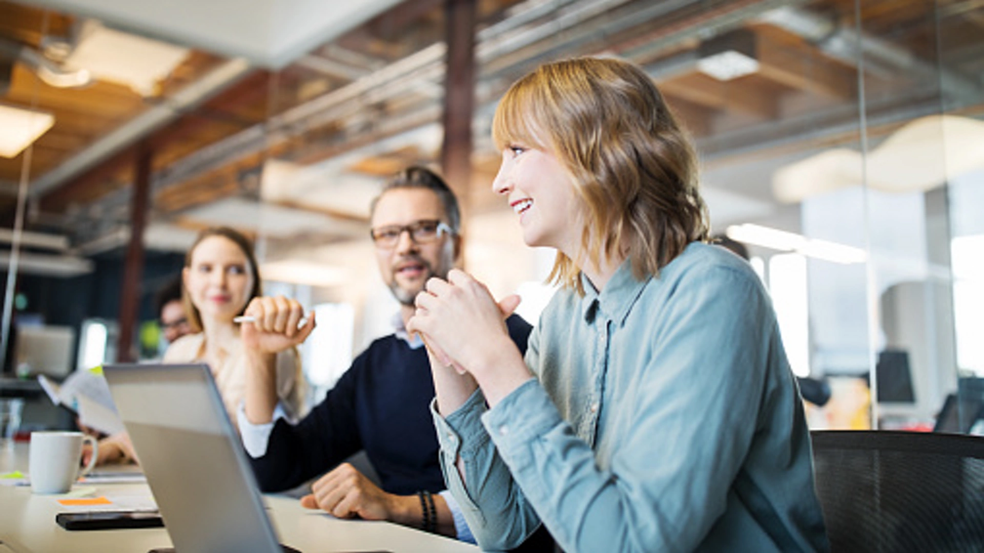 Young businesswoman discussing with coworker in meeting. Group of business professionals working together in office.