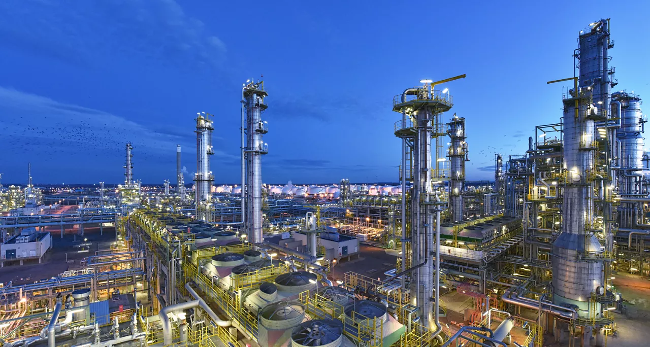 large-industrial-refinery-complex-with-distillation-columns-pipelines-processing-units-and-storage-facilities-illuminated-at-dusk-under-blue-sky